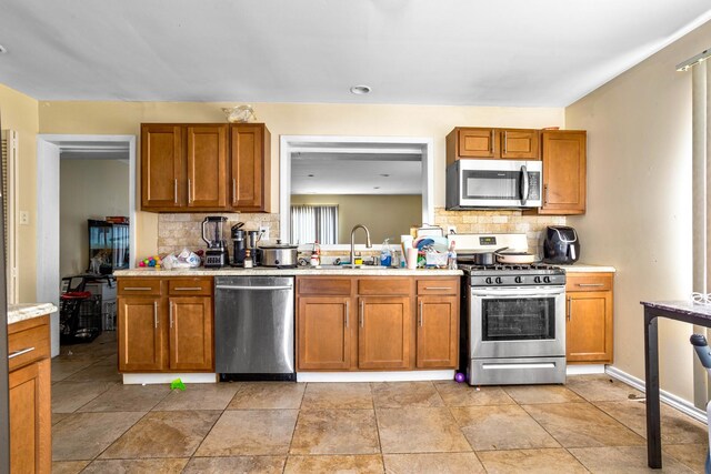 kitchen with light countertops, a sink, backsplash, and stainless steel appliances
