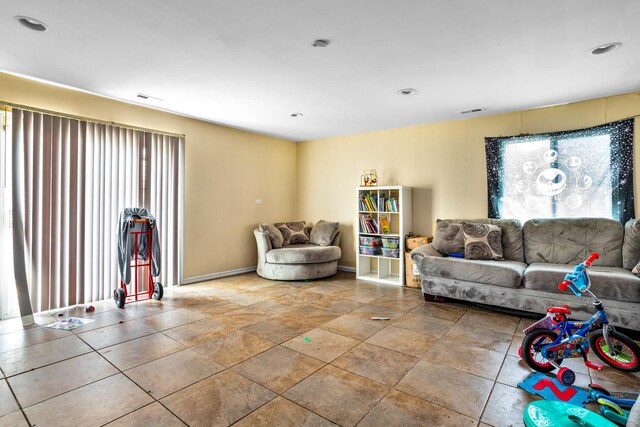 living area featuring baseboards, stone finish floor, recessed lighting, and visible vents