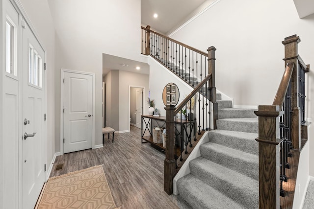 foyer entrance with recessed lighting, a high ceiling, wood finished floors, baseboards, and stairs
