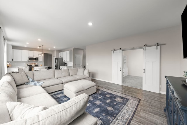 living room featuring a barn door, wood finished floors, baseboards, and recessed lighting