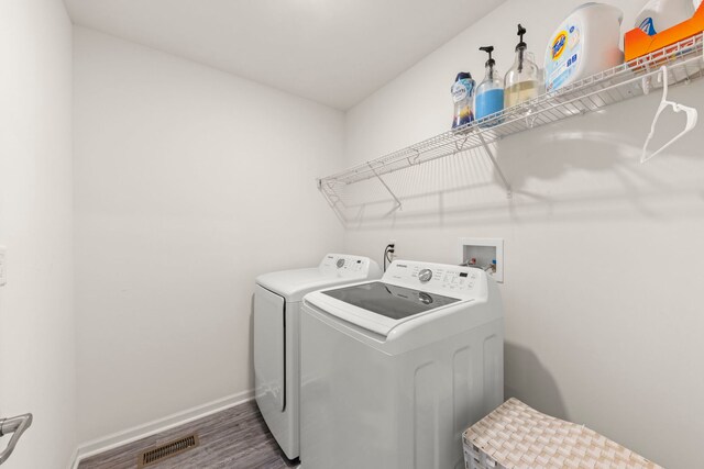 laundry room featuring laundry area, wood finished floors, visible vents, baseboards, and separate washer and dryer