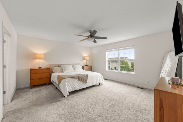 carpeted bedroom with baseboards, a ceiling fan, and visible vents