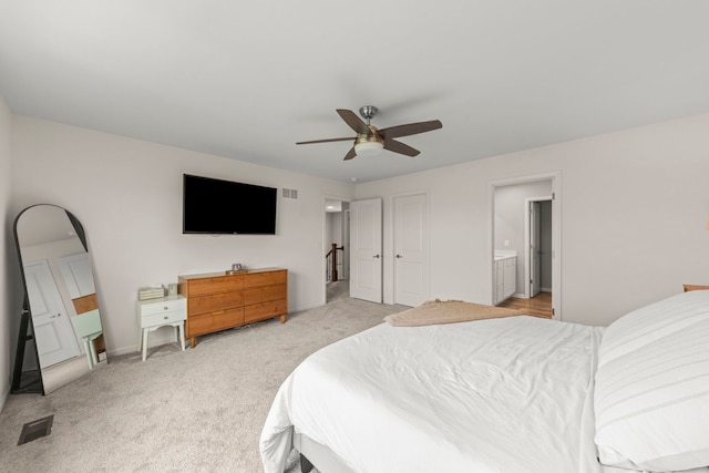 bedroom with ensuite bath, light carpet, a ceiling fan, and visible vents