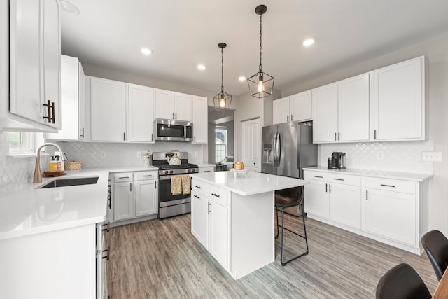 kitchen featuring stainless steel appliances, a center island, a sink, decorative backsplash, and a breakfast bar area