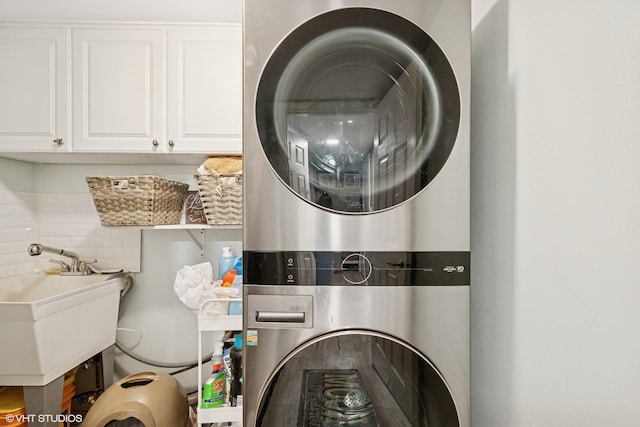 washroom with cabinet space and stacked washer / dryer