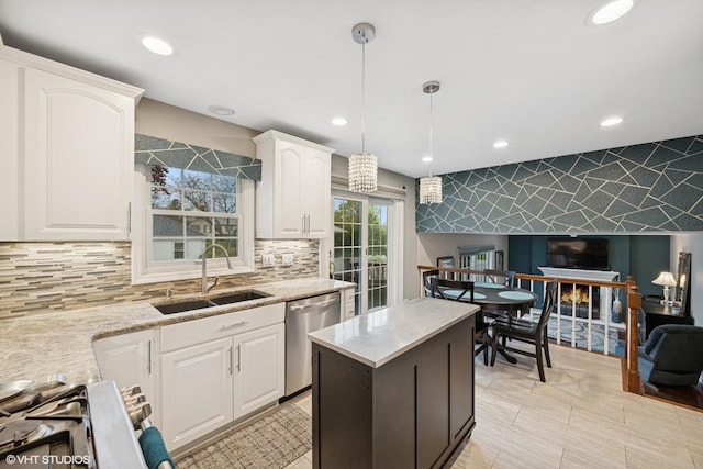 kitchen with appliances with stainless steel finishes, tasteful backsplash, hanging light fixtures, a sink, and white cabinetry