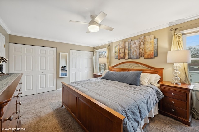 bedroom with ornamental molding, carpet, ceiling fan, and two closets