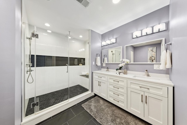 bathroom featuring a shower stall, double vanity, visible vents, and a sink