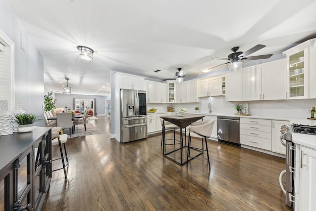 kitchen with a ceiling fan, a sink, stainless steel appliances, white cabinetry, and dark wood-style flooring
