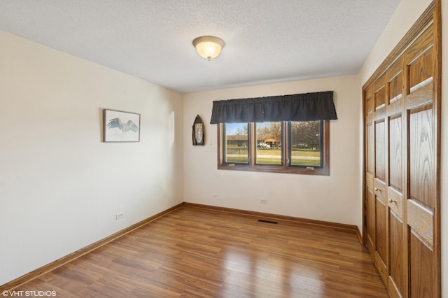 12524 Grandview Dr, Huntley, IL 60142 - unfurnished bedroom with wood finished floors, baseboards, and a textured ceiling