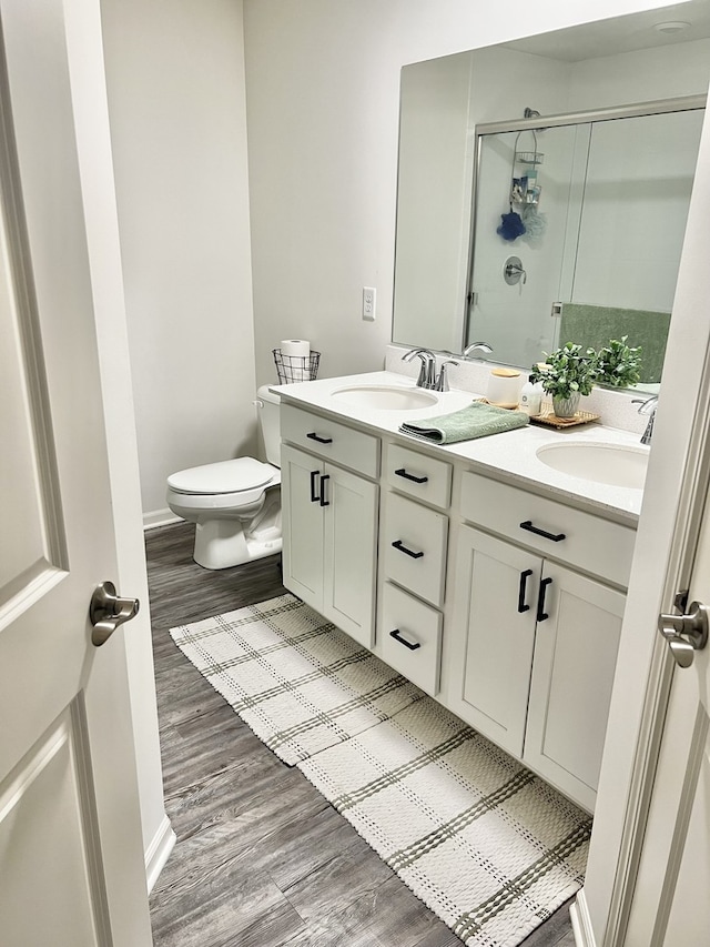 full bath with wood finished floors, a sink, a shower stall, and toilet