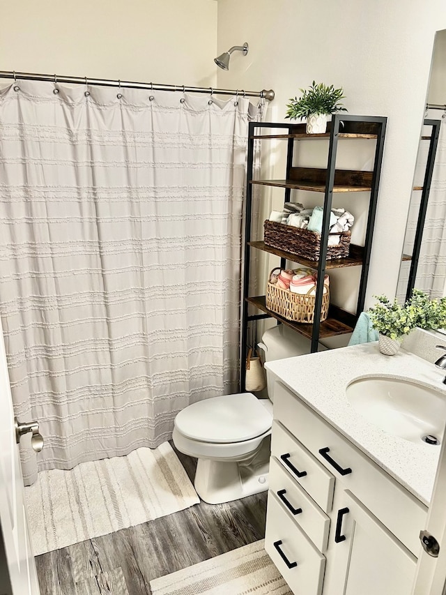 full bath with toilet, vanity, wood finished floors, and curtained shower