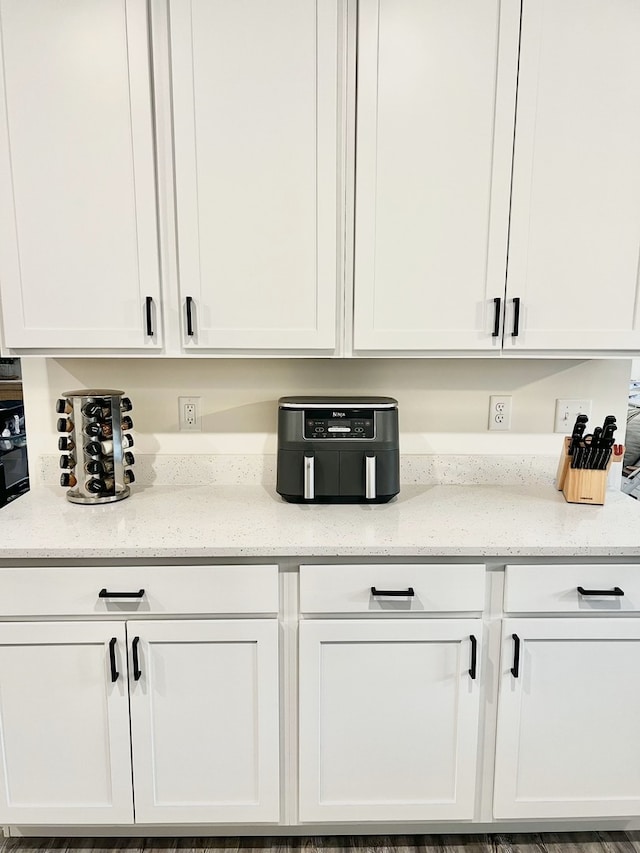 kitchen with white cabinetry and light stone counters