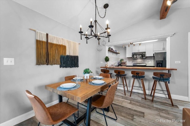 dining room featuring lofted ceiling with beams, baseboards, a chandelier, and wood finished floors