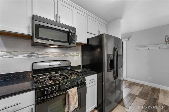 kitchen featuring wood finished floors, stainless steel appliances, backsplash, baseboards, and white cabinetry
