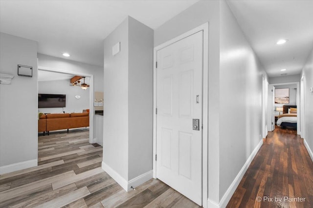 hallway with baseboards, wood finished floors, and recessed lighting