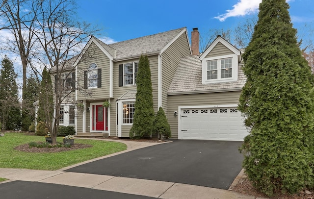 colonial-style house with a garage, driveway, and a chimney