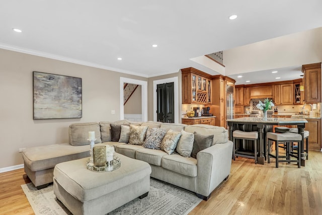 living area featuring baseboards, crown molding, light wood-style floors, and recessed lighting