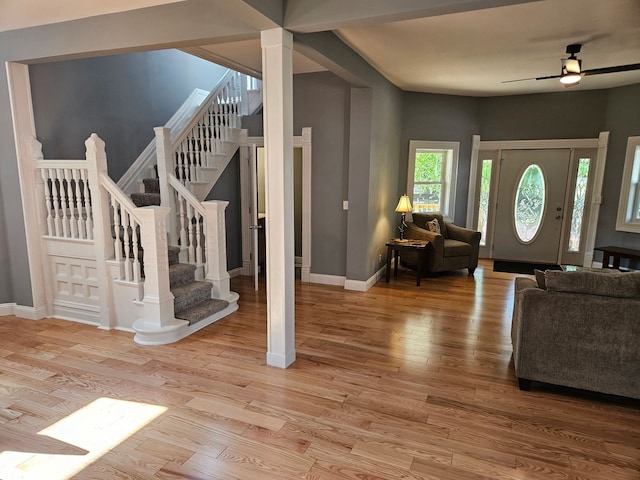 living room featuring baseboards, stairway, light wood-type flooring, and a ceiling fan