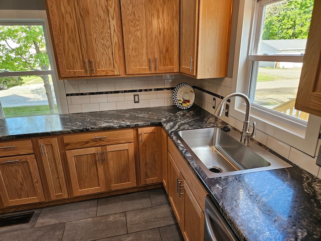kitchen featuring a sink, healthy amount of natural light, backsplash, and brown cabinets