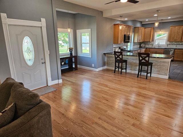 foyer featuring light wood finished floors, baseboards, healthy amount of natural light, a ceiling fan, and recessed lighting