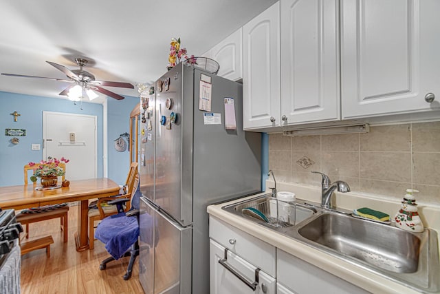 kitchen with tasteful backsplash, a sink, ceiling fan, white cabinets, and freestanding refrigerator