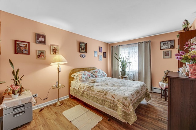 bedroom featuring a baseboard radiator, wood finished floors, and baseboards