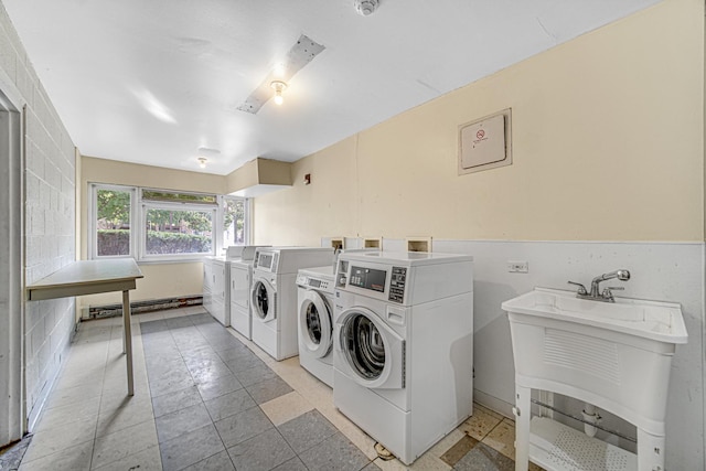 shared laundry area with a baseboard heating unit, washing machine and clothes dryer, and a sink