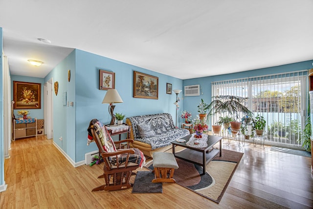living area with light wood-style flooring, baseboards, and a wall unit AC