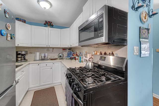 kitchen featuring decorative backsplash, white cabinetry, stainless steel appliances, and light countertops