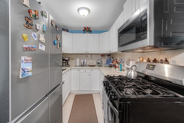 kitchen with white cabinets, light tile patterned floors, appliances with stainless steel finishes, and tasteful backsplash
