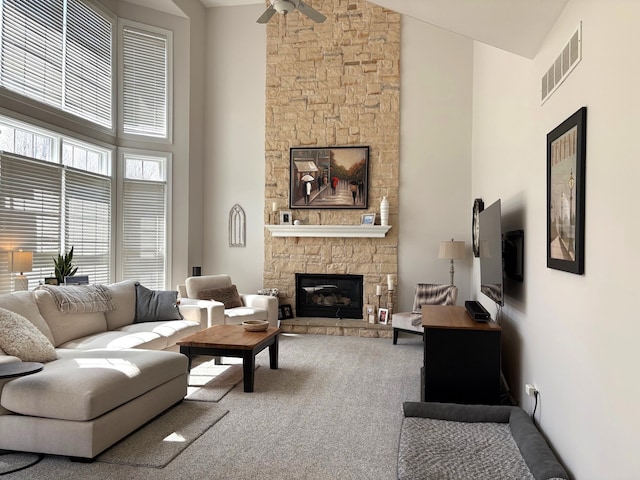 carpeted living area with visible vents, a ceiling fan, high vaulted ceiling, and a fireplace