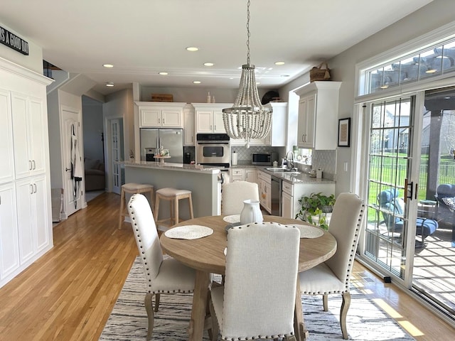 dining space featuring light wood-style floors, recessed lighting, and a chandelier