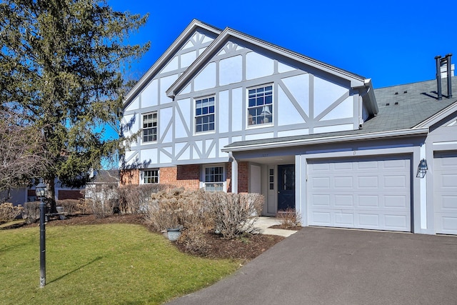 english style home with aphalt driveway, a front lawn, brick siding, and stucco siding
