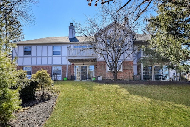 rear view of property featuring a chimney, brick siding, and a yard