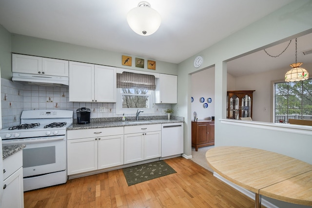 kitchen featuring white cabinets, tasteful backsplash, under cabinet range hood, and white appliances