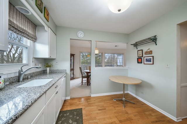 kitchen featuring a wealth of natural light, white cabinetry, a sink, and light wood-style floors
