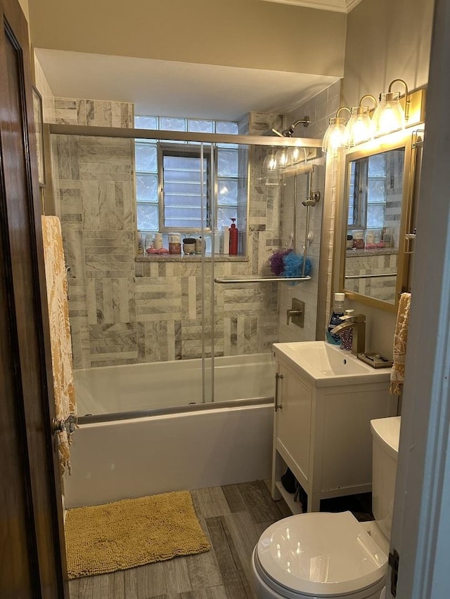 full bathroom with toilet, wood finished floors, bath / shower combo with glass door, and vanity
