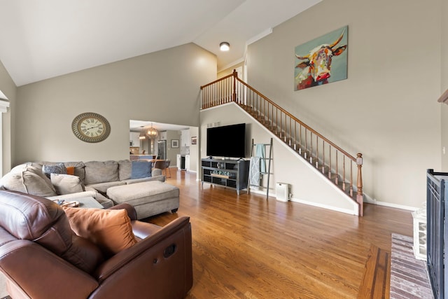 living room featuring high vaulted ceiling, wood finished floors, stairway, and baseboards