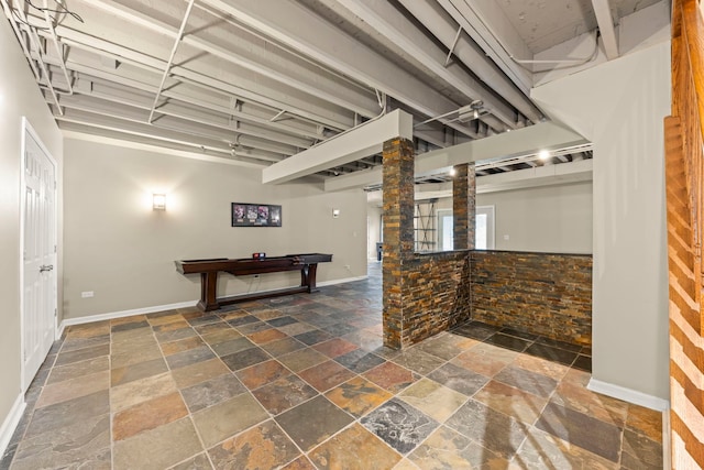 finished basement featuring stone tile flooring, billiards, and baseboards