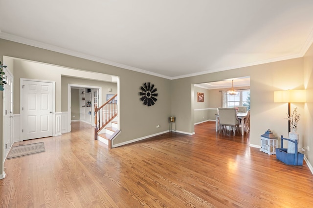living area with crown molding, light wood-type flooring, a chandelier, stairway, and baseboards