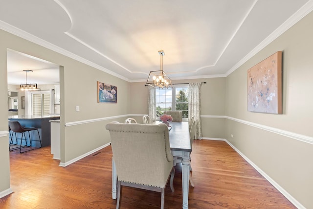 dining area featuring a chandelier, wood finished floors, baseboards, and crown molding