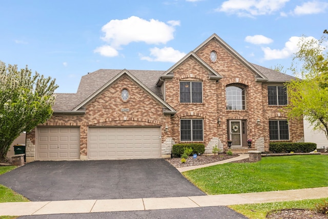 view of front of property featuring an attached garage, driveway, brick siding, and a front yard