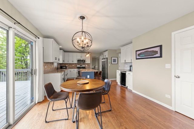 dining space with a chandelier, light wood-style floors, and baseboards