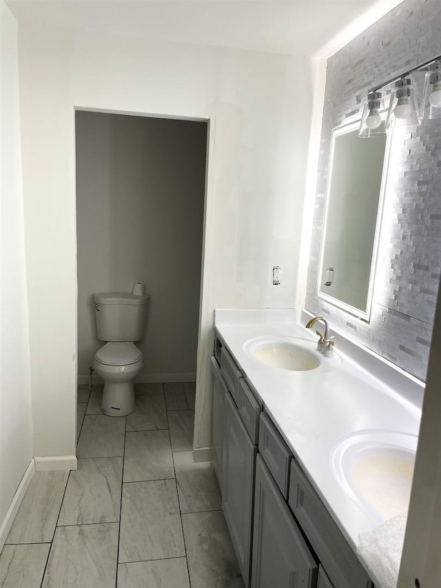 full bathroom featuring double vanity, marble finish floor, toilet, and a sink