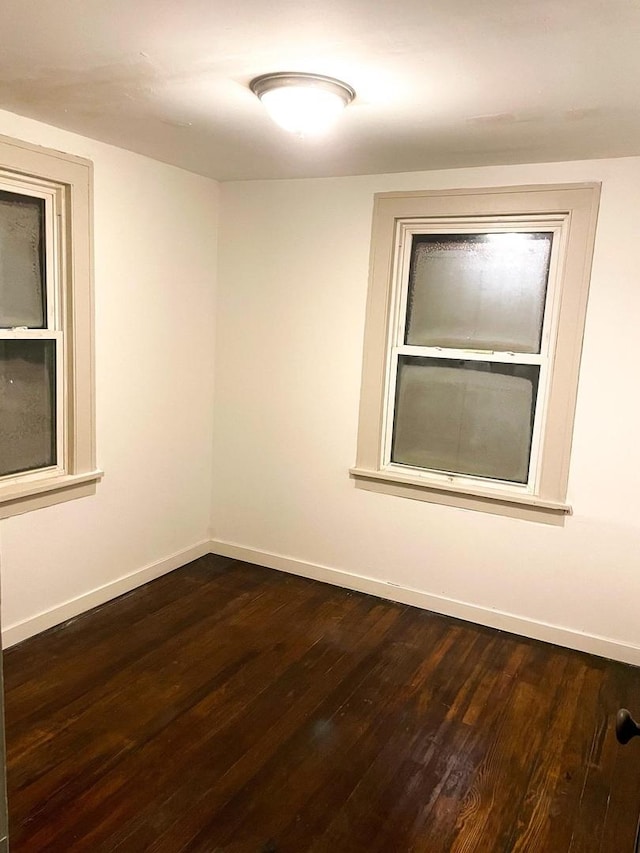 empty room with baseboards and dark wood-style flooring