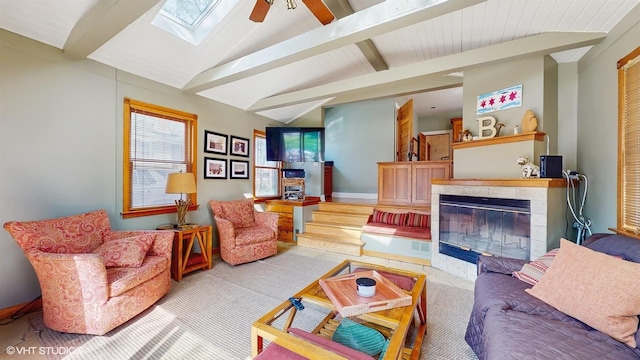 living area with baseboards, a ceiling fan, lofted ceiling with skylight, and a fireplace