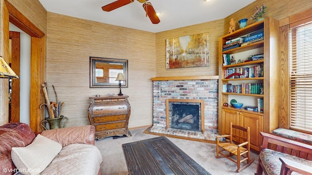 carpeted living room with a brick fireplace and a ceiling fan