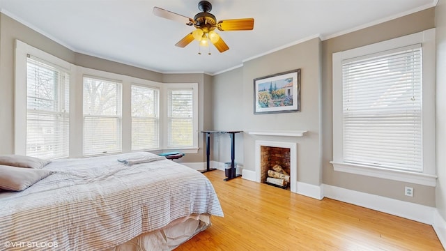 bedroom with ceiling fan, light wood-type flooring, ornamental molding, and baseboards