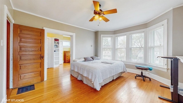 bedroom with baseboards, visible vents, ornamental molding, and light wood-type flooring